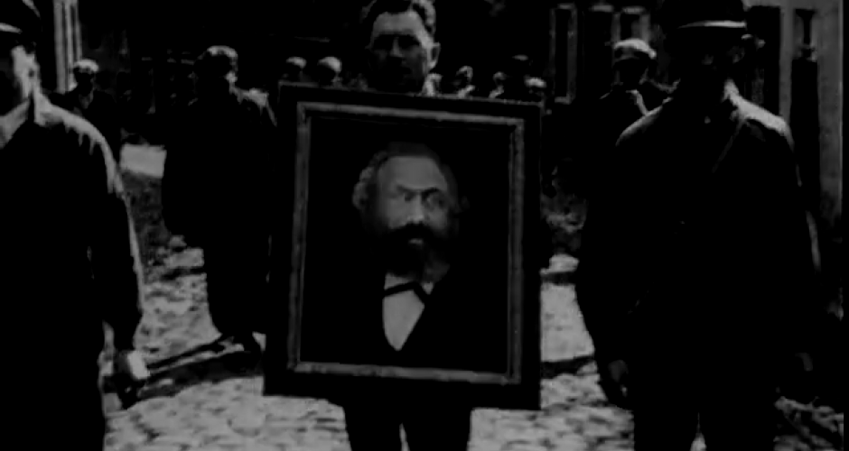 man holding a portrait of Karl Marx during a demonstration