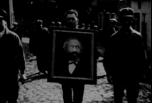 man holding a portrait of Karl Marx during a demonstration